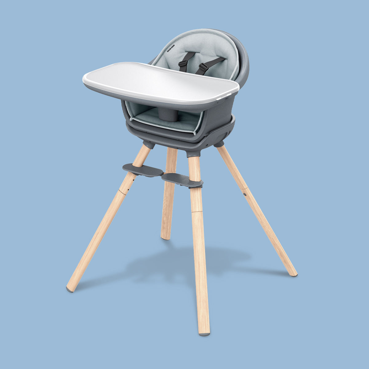 A Maxi-Cosi Moa 8-in-1 High Chair with a wooden base on a blue background, designed for multi-use.
