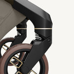 Close-up of a stroller wheel and suspension system on a white background