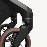 Close-up of a stroller wheel and suspension mechanism on a white background