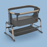 A gray Maxi-Cosi Iora Air co-sleeping bassinet with a thick mattress and a storage basket underneath, set against a blue background.